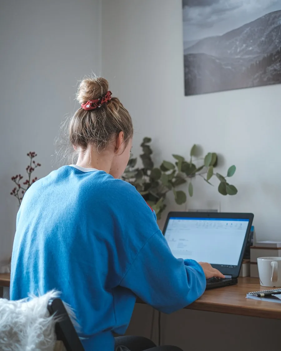 Formateur indépendant en situation, travaillant sur son ordinateur portable dans un espace de travail lumineux.