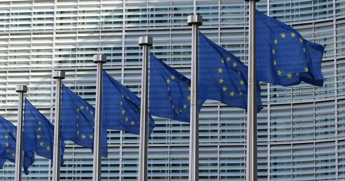 Bâtiment institutionnel européen et drapeaux — le cadre réglementaire de l'AI Act pour la formation.