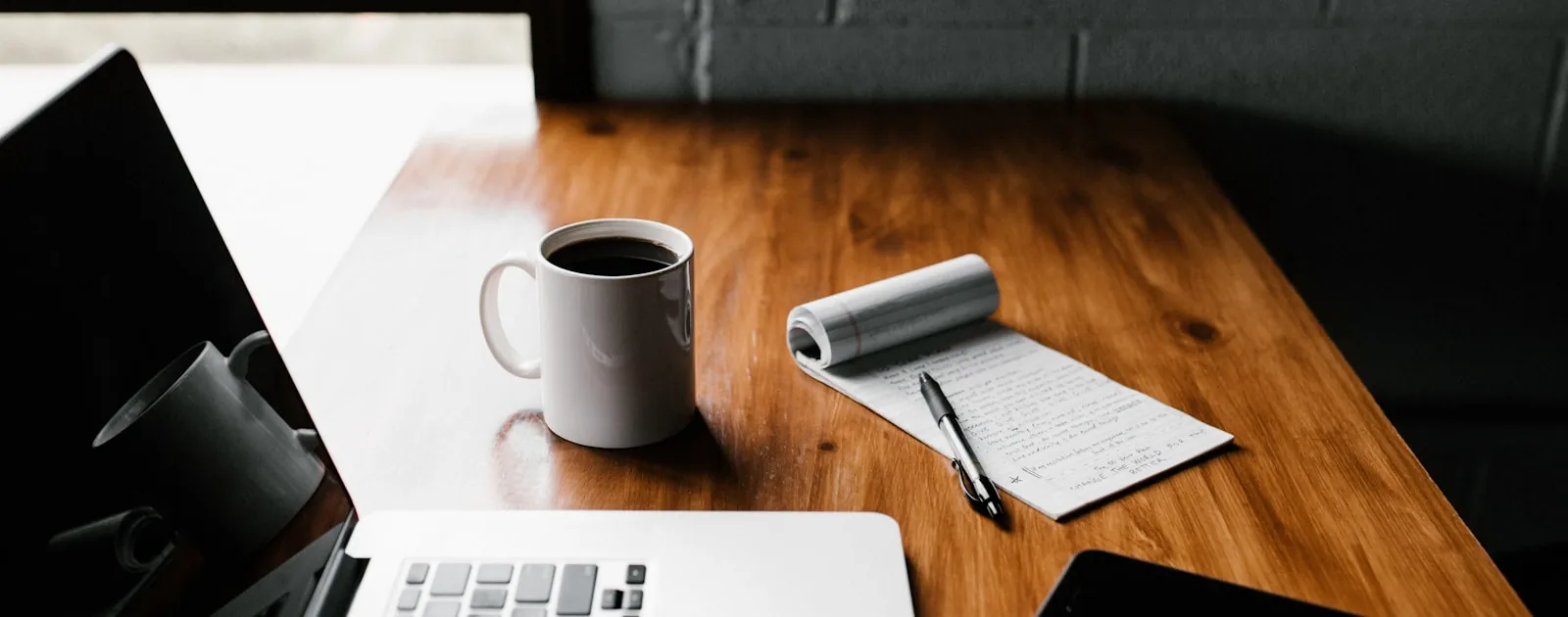 Concepteur pédagogique au travail sur un ordinateur portable, écran d'édition et carnet de notes