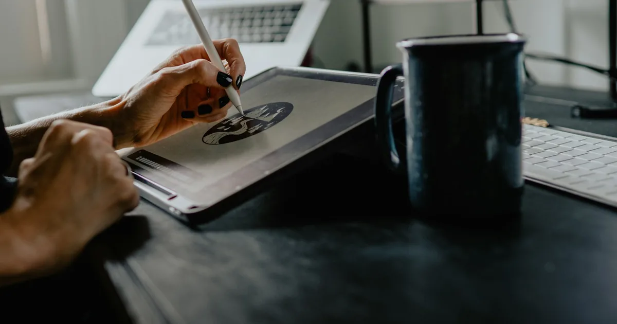 Concepteur pédagogique au travail sur ordinateur portable, carnet de notes et croquis — l'outil-auteur à l'ère de l'IA.